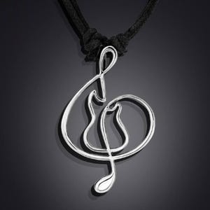 K&ouml;nnte beinhalten: Eine silberne Violinschl&uuml;ssel-Anh&auml;nger-Halskette mit einem schwarzen Band. Der Anh&auml;nger ist ein schlichtes, elegantes Design.