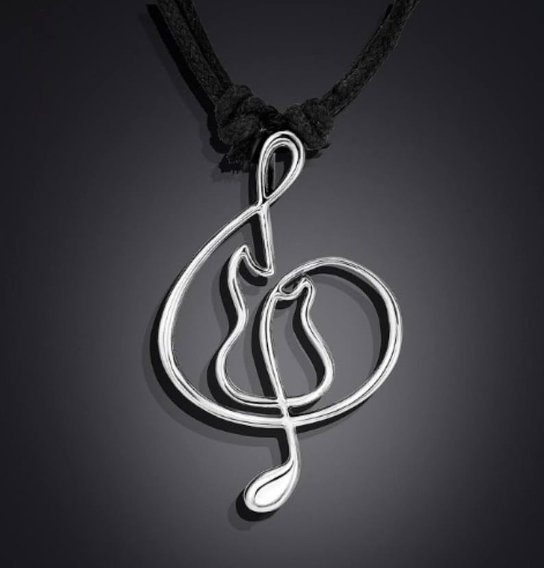 K&ouml;nnte beinhalten: Eine silberne Violinschl&uuml;ssel-Anh&auml;nger-Halskette mit einem schwarzen Band. Der Anh&auml;nger ist ein schlichtes, elegantes Design.