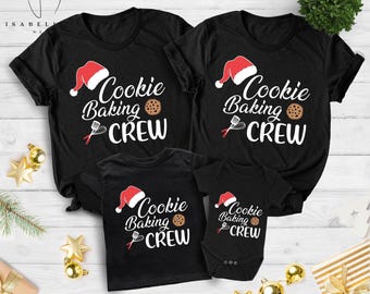 May include: Black t-shirts and a onesie with the text "Cookie Baking Crew" in white script, a Santa hat, a cookie, and a spatula. The shirts are for a family, perfect for Christmas. The onesie is for a baby.