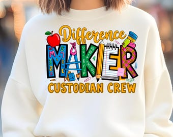 Könnte beinhalten: Cremefarbenes Sweatshirt mit einem farbenfrohen Aufdruck "Difference Maker Custodian Crew". Das Design beinhaltet einen Apfel, einen Bleistift und andere schulbezogene Elemente. Ein bequemes Kleidungsstück.