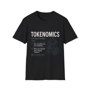Op de afbeelding: Een zwart t-shirt met korte mouwen en een witte en lichtblauwe grafische print. Het ontwerp toont het woord TOKENOMICS, een fonetische uitspraak en een definitie in woordenboekstijl met de tekst The invisible tax on creativity.