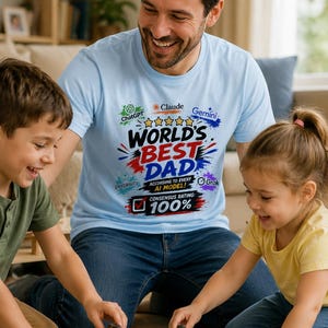 May include: A light blue t-shirt featuring a graphic print with the text "WORLD'S BEST DAD" in large letters, surrounded by logos for ChatGPT, Claude, Gemini, Perplexity, and Grok, with the additional text "ACCORDING TO EVERY AI MODEL!" and "CONSENSUS RATING: 100%".