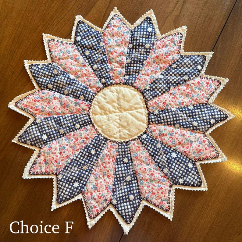 May include: A handmade, starburst-shaped quilted item with a cream-colored center and alternating segments of floral and navy blue star-patterned fabric. The edges are finished with a white, scalloped trim. The text "Choice F" is at the bottom.