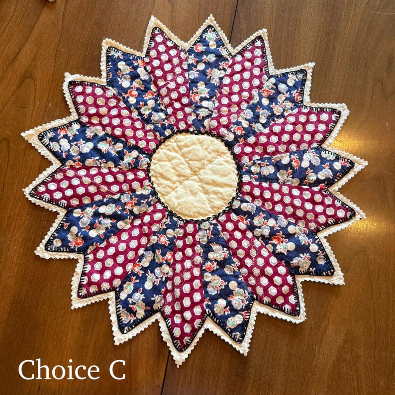 May include: A handmade, flower-shaped quilted trivet with a cream-colored center and alternating burgundy and navy blue petal sections. The petals feature floral and polka dot patterns, with a scalloped white lace edge. The text "Choice C" is at the bottom.