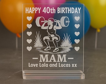 Op de afbeelding: Transparante acryl verjaardagsplaat met de tekst "HAPPY 40th BIRTHDAY" en een gewichtheffen grafiek. De plaat bevat ook het woord "MAM" en de namen "Love Lola and Lucas xx". Witte hart- en grasafbeeldingen zijn ook inbegrepen.