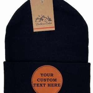 Peut inclure: Bonnet noir en tricot avec un patch en cuir marron qui dit "YOUR CUSTOM TEXT HERE".