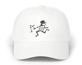 May include: A white baseball cap featuring a black graphic print of a stylized, spindly figure running while holding a pitchfork and a knife, accompanied by several small musical note symbols floating near the figure's outstretched hand.
