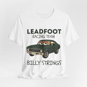 May include: White t-shirt featuring a cartoon illustration of a green classic car with eyes. The text "LEADFOOT RACING TEAM" and "BILLY STRINGS" are printed above and below the car graphic.