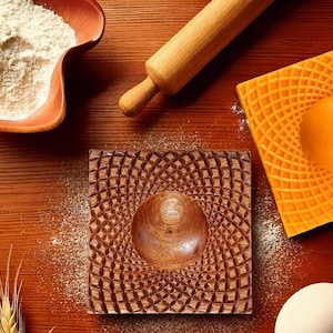May include: Two wooden molds for baking, one with a brown wood grain pattern and the other with a bright orange pattern. Both molds have a circular indentation in the center.