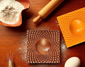 May include: Two wooden molds for baking, one with a brown wood grain pattern and the other with a bright orange pattern. Both molds have a circular indentation in the center.