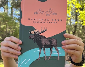 May include: A National Park Explorer's Guide book with a moose illustration on the cover. The cover features a salmon-colored top section with mountain silhouettes, a dark green bottom section, and the title in a serif font.