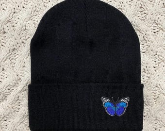 May include: Black beanie with a blue butterfly embroidered on the front.