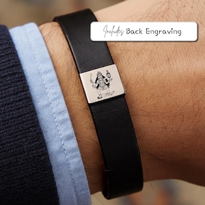 May include: A black leather bracelet featuring a square silver-toned metal charm engraved with a detailed illustration of the goddess Kali holding a sword and a severed head. A white rectangular label displays the text Includes Back Engraving.