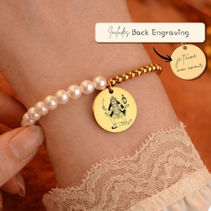 May include: A bracelet featuring a half-strand of white pearls and a half-strand of gold-toned beads. A circular gold-toned pendant displays a black engraved illustration of the goddess Kali. A separate circular tag shows the text Je t'aime mon amour.