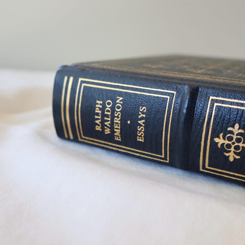 Puede incluir: Un libro encuadernado en cuero negro con letras doradas en el lomo. El t&iacute;tulo dice "Ralph Waldo Emerson Essays".
