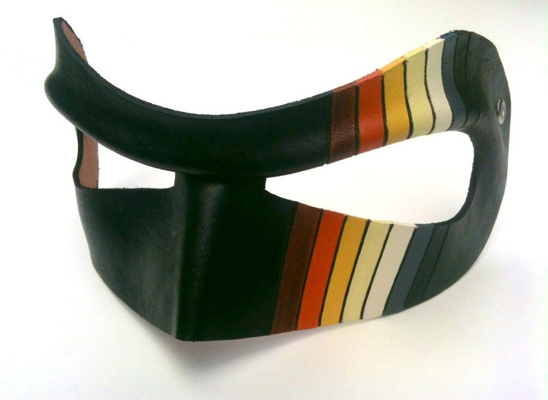 May include: A black leather mask with a rainbow stripe design. The mask has a large eye opening and a small opening for the nose.