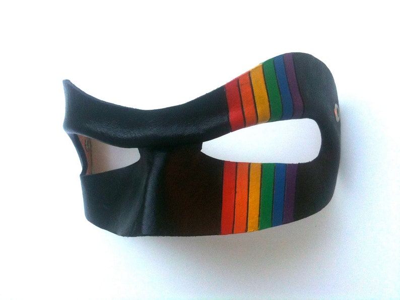 May include: A black leather mask with a rainbow stripe design. The mask has a single eye hole and is designed to cover the eyes and nose.