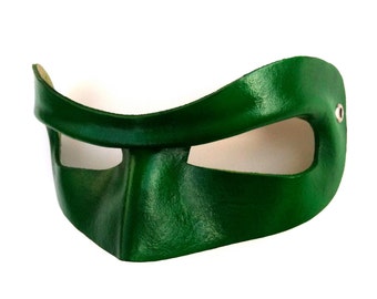 Può includere: Una maschera per gli occhi in pelle verde con un solo foro per l'occhio e un rivetto argentato sul lato.