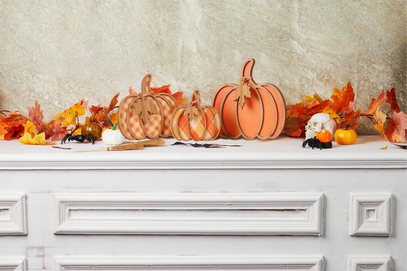 Three wooden pumpkin decorations on a mantle