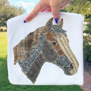 Pode incluir: Saco tote branco com um design de cabeça de cavalo em patchwork. A cabeça do cavalo é composta por tecidos castanhos, azuis e cinzentos, costurados. O design está centrado no saco.