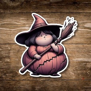May include: A sticker featuring a cartoon witch with a large hat and a broom. The witch is wearing a pink dress and has a round body. The background is a wooden surface.