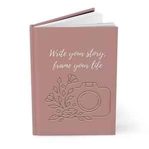 May include: A dusty rose journal with the text "Write your story, frame your life" and a line drawing of a camera with flowers.