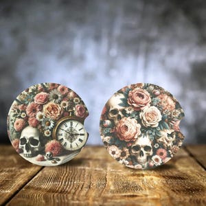 May include: Two round coasters with a floral and skull design. One coaster features a pocket watch with roman numerals. Both coasters have a vintage aesthetic.