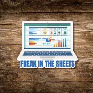 May include: White laptop sticker with a spreadsheet graphic on the screen. The sticker has the text "FREAK IN THE SHEETS" in blue block letters. The background is a wooden surface.