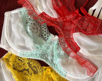 May include: An assortment of colorful bras in white, red, yellow, and mint green. The bras feature lace and floral details. The red bra has a satin finish. The bras are arranged on a red surface.