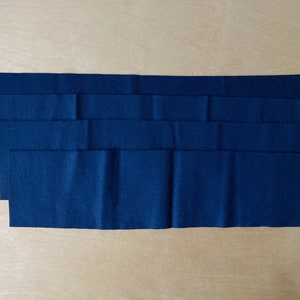 Puede incluir: Cinco tiras de tela azul oscuro apiladas una encima de la otra.