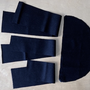 Puede incluir: Tres tiras de tela negra y un semicírculo de tela negra. Las tiras miden aproximadamente 25 cm de largo y 5 cm de ancho. El semicírculo tiene un diámetro de aproximadamente 25 cm.