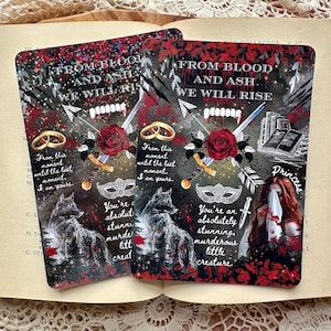 Könnte beinhalten: Zwei Lesezeichen mit einem dunklen Hintergrund und roten Akzenten. Die Lesezeichen zeigen einen Wolf, eine Rose, einen Dolch, eine Maske und einen Ring. Der Text auf den Lesezeichen lautet "From Blood and Ash, We Will Rise." und "You're an absolutely stunning, murderous little creature."