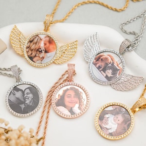 May include: Five gold, silver and rose gold photo pendants with diamond accents. Each pendant features a different photo of a couple, a pet and a baby. The pendants are on chains with a rope chain design.