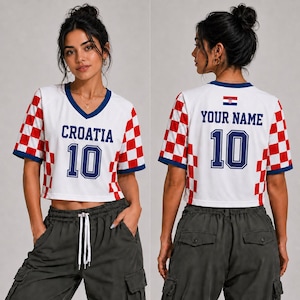 May include: A white V-neck crop top featuring red and white checkered patterns on the sleeves and sides. The front displays the text CROATIA and the number 10 in blue. The back shows the text YOUR NAME, the number 10, and a small Croatian flag.