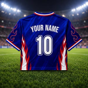 May include: A blue soccer jersey with white and red flame designs on the sides. The jersey has the text "YOUR NAME" above the number "10" on the back. The jersey has a white collar with red and blue stripes.