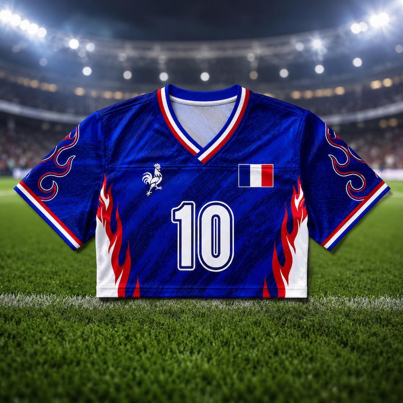 May include: A blue soccer jersey with white and red accents, featuring the number 10 in white. The jersey has a V-neck and a French flag patch. Red and white flame designs are on the sides. A rooster emblem is on the chest.
