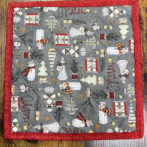 May include: A square, quilted Christmas-themed potholder with a gray background and a red border. The fabric is patterned with various holiday motifs, including snowmen, Christmas trees, and gift boxes. The potholder is approximately 8 inches square.