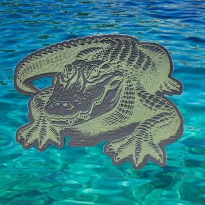 May include: A detailed illustration of an alligator in shades of green and gray, set against a backdrop of blue water. The alligator is depicted with textured scales and a detailed face, giving it a realistic appearance. The image has a vintage, artistic style.