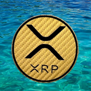 May include: A gold-colored XRP cryptocurrency coin with a black border and the XRP symbol, set against a backdrop of blue water. The coin has a textured surface and the letters "XRP" are visible.