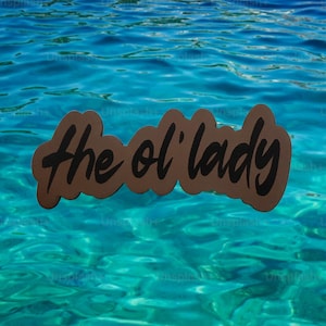 May include: A brown, cloud-shaped sticker with the words "the ol' lady" in black script. The sticker floats against a backdrop of rippling turquoise water.