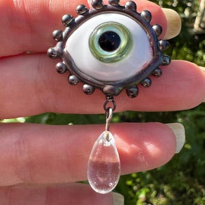 Handmade flamework glass eye brooch with clear glass tear.