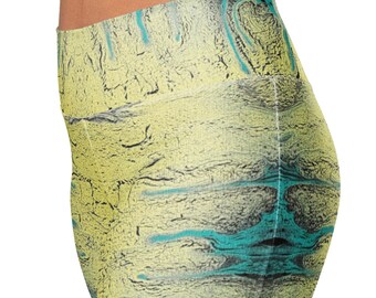 May include: High-waisted leggings with an abstract design. The leggings feature a yellow base with black, teal, and gray patterns. The fabric appears to have a textured, marbled effect, creating a unique visual appeal. The leggings are form-fitting and suitable for various activities.