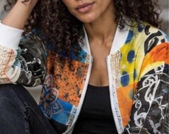 May include: A bomber jacket featuring a vibrant, multi-colored patchwork design with abstract patterns in shades of orange, blue, yellow, and black. The jacket has a white ribbed collar, white sleeve cuffs, and a full-length front zipper closure.