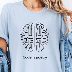 Könnte beinhalten: Ein hellblaues T-Shirt mit einer schwarzen Umrandung eines Gehirns mit Schaltkreis-Mustern im Inneren. Der Text "Code is poetry" ist unter dem Gehirn aufgedruckt.
