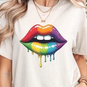 Könnte beinhalten: Ein weißes T-Shirt mit einem bunten, tropfenden Lippen-Motiv. Die Lippen sind in Lila umrandet und mit einem Regenbogenmuster gefüllt.