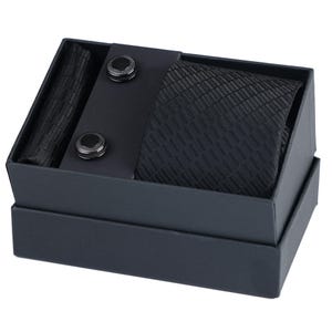 May include: A black tie set with a patterned tie, two cufflinks, and a pocket square, all packaged in a black box.