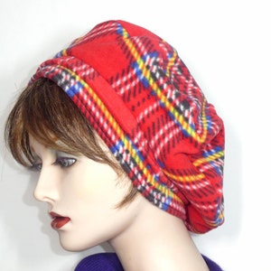 May include: Red fleece beret with a plaid pattern in black, white, blue and yellow.