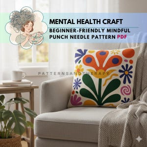 May include: A decorative throw pillow with a colorful floral design, featuring orange, blue, yellow, and green elements. The pillow is on a light gray armchair, with a neutral-toned blanket draped over it. The image includes text: "MENTAL HEALTH CRAFT, BEGINNER-FRIENDLY MINDFUL PUNCH NEEDLE PATTERN PDF."