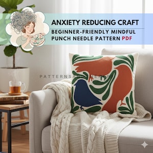 Könnte beinhalten: Ein dekoratives Kissen mit einem Vogeldesign in Orange, Blau und Grün, das auf einer cremefarbenen Strickdecke liegt. Das Kissen befindet sich auf einem hellgrauen Sofa. Text auf dem Bild: Anxiety Reducing Craft, Beginner-Friendly Mindful Punch Needle Pattern PDF.