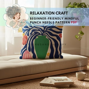 Könnte beinhalten: Ein dekoratives Kissen mit einem farbenfrohen, abstrakten Design, das eine grüne Vase und blaue, weiße und rosa Elemente zeigt. Das Kissen liegt auf einem beigen Kissen. Der Text auf dem Bild lautet "RELAXATION CRAFT BEGINNER-FRIENDLY MINDFUL PUNCH NEEDLE PATTERN PDF".